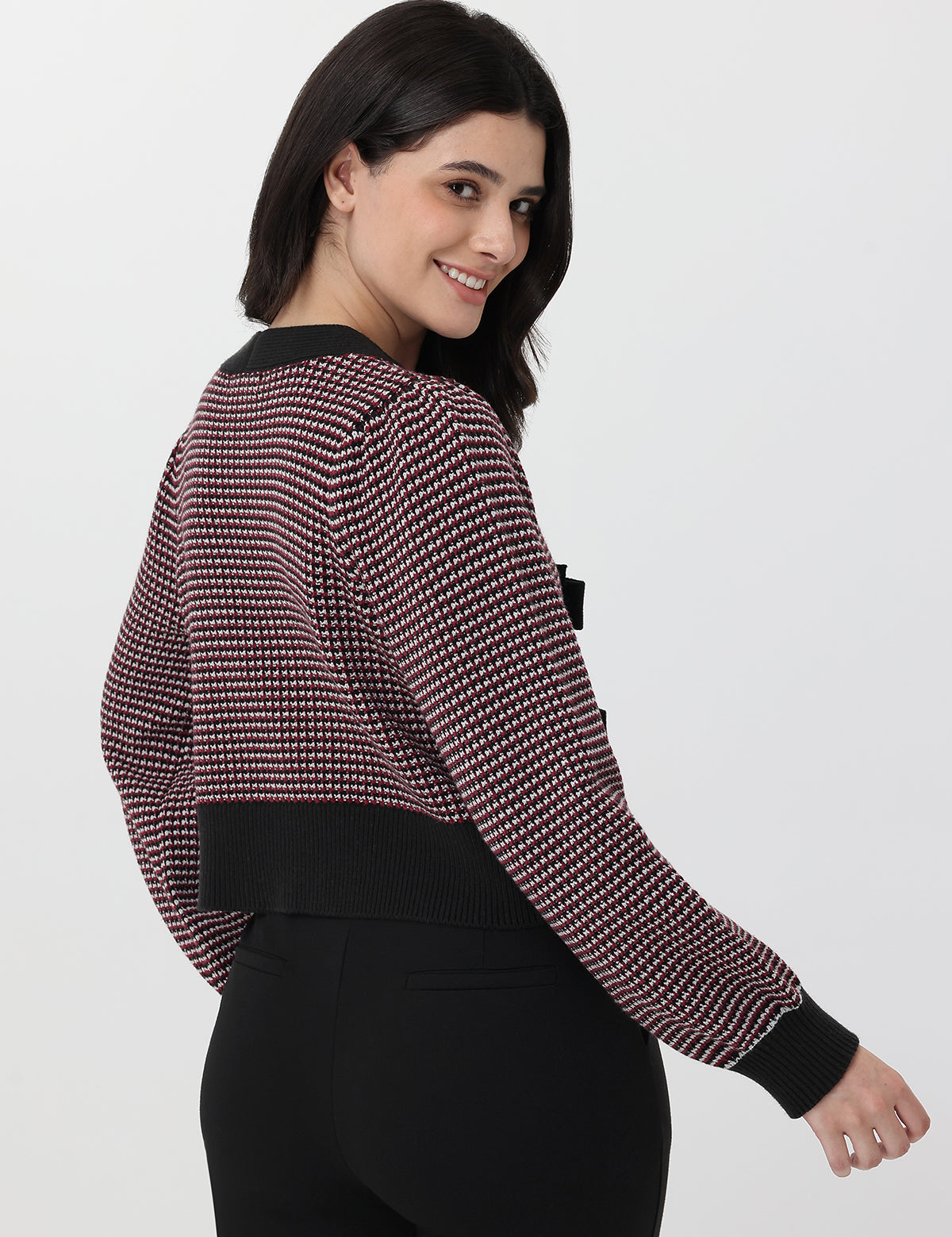 Woman wearing a patterned long-sleeve cardigan with deep garnet accents on a white background