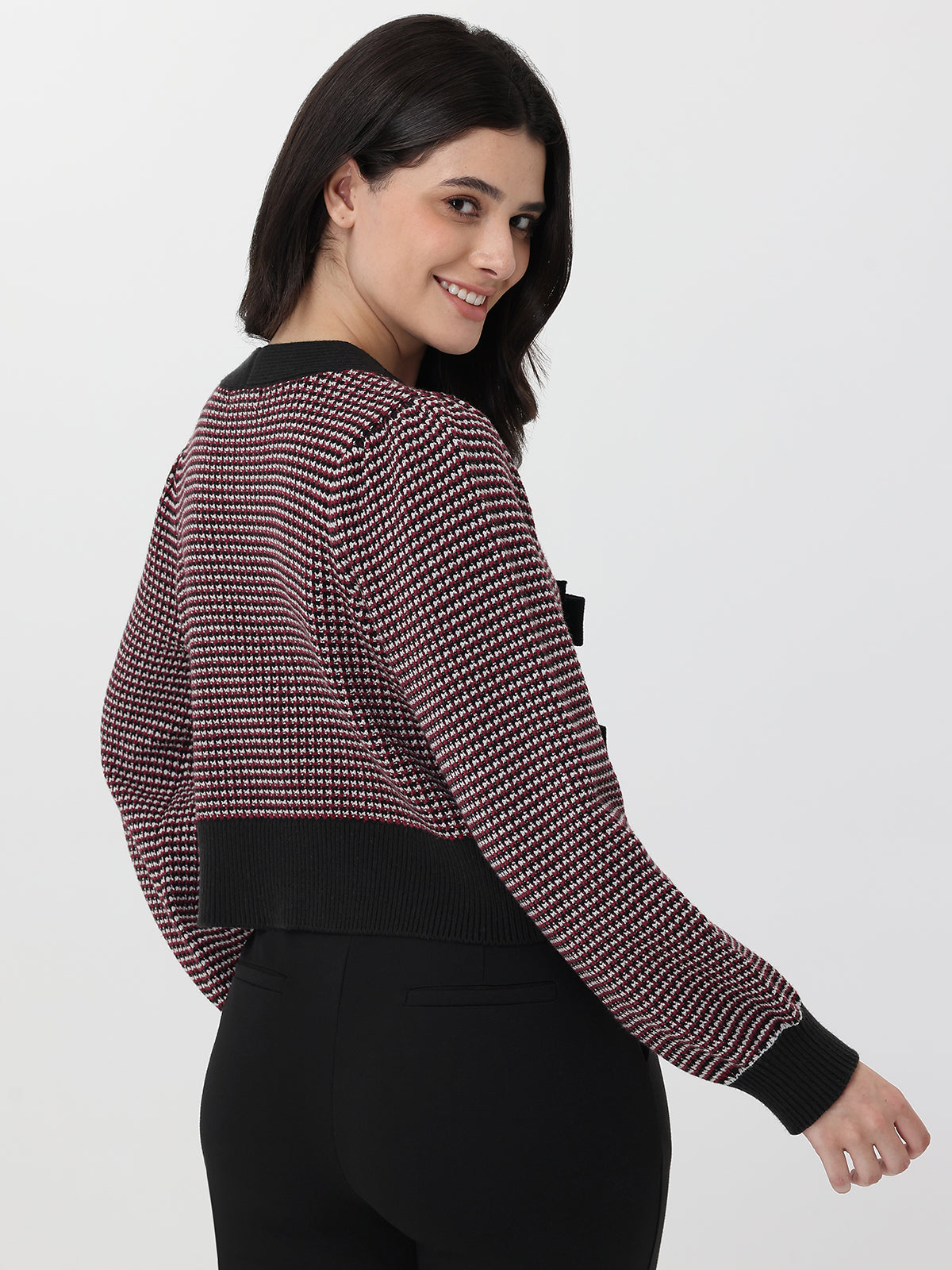 Woman wearing a patterned long-sleeve cardigan with deep garnet accents on a white background