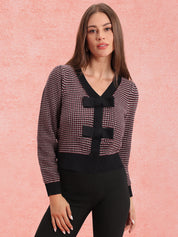 Woman wearing a patterned cardigan over a deep garnet cardigan against a pink background