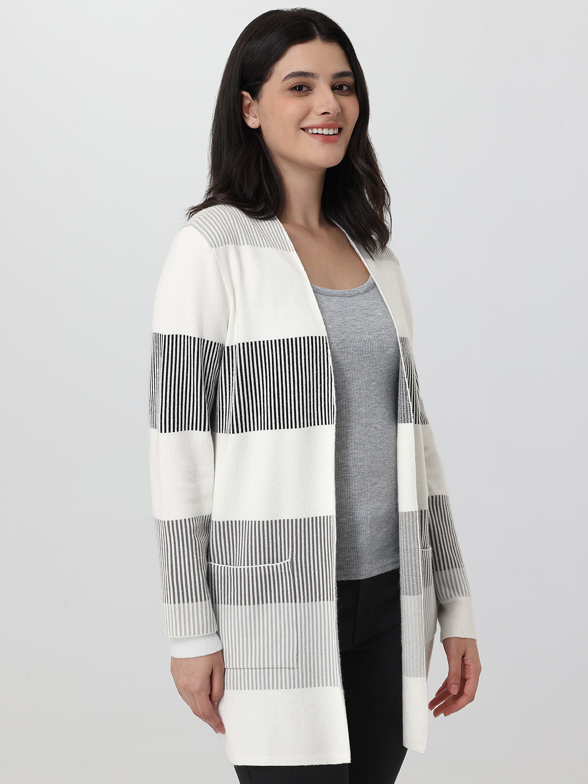 Woman wearing a long, striped cardigan on a plain background