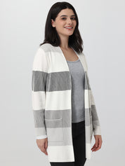 Woman wearing a long, striped cardigan on a plain background