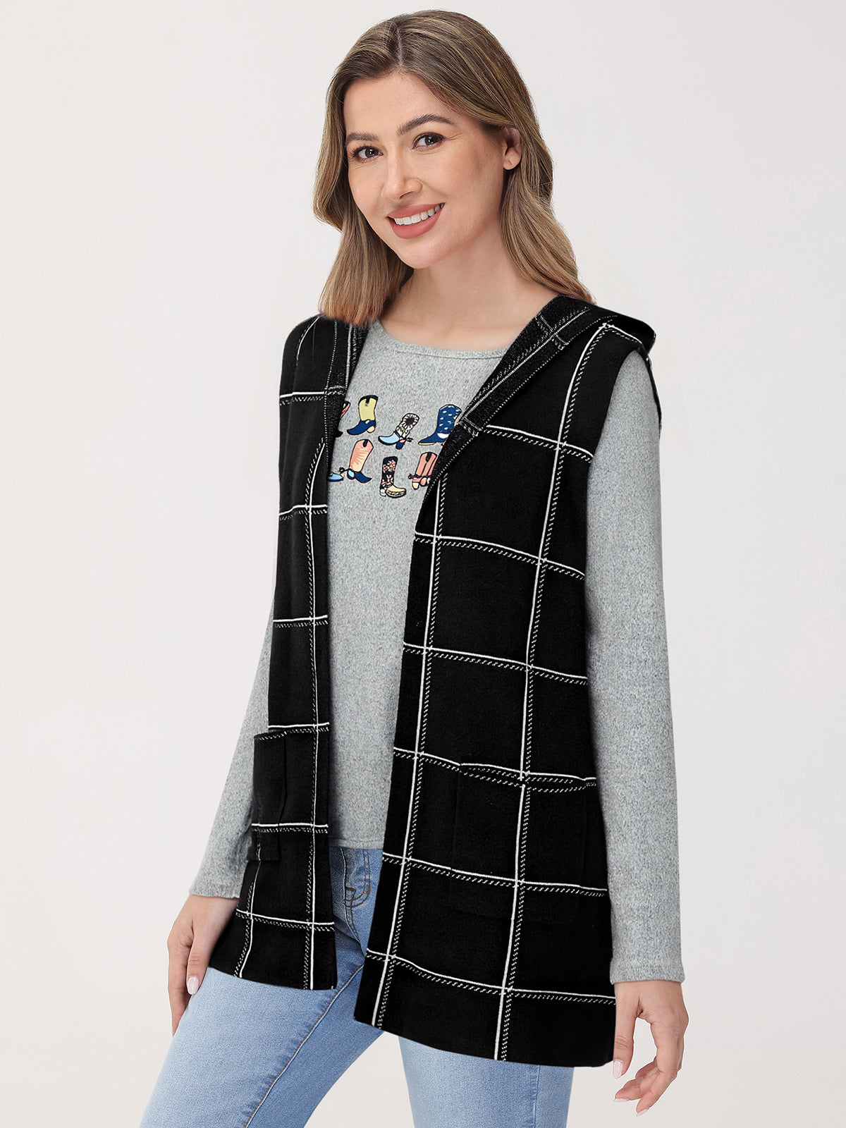 Woman wearing a black checkered vest over a gray long-sleeve shirt with a graphic design on a white background