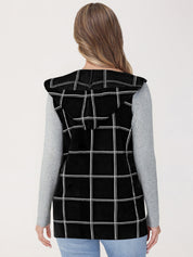 Person wearing a black checkered vest on a light gray background