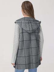 Woman wearing a gray checkered coat with a hood on a white background