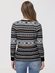 Person wearing a black patterned sweater on a plain background