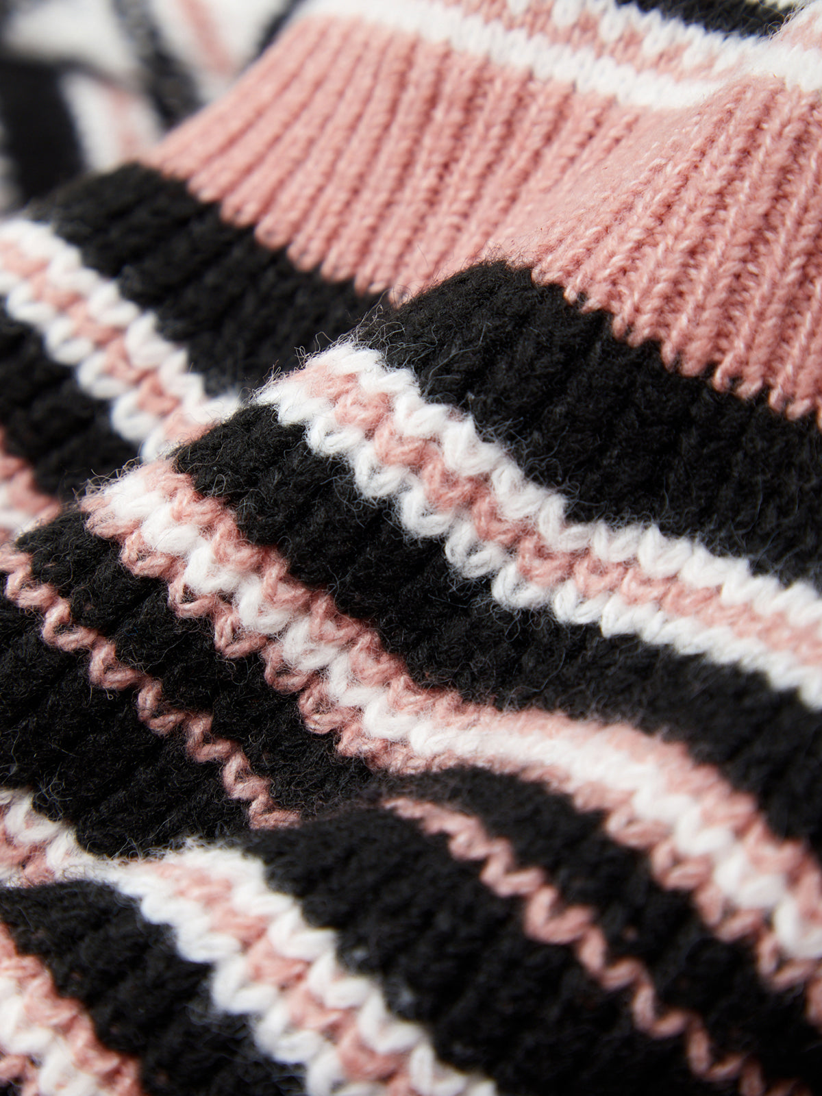 Close-up of a knitted fabric with black, pink, and white stripes.