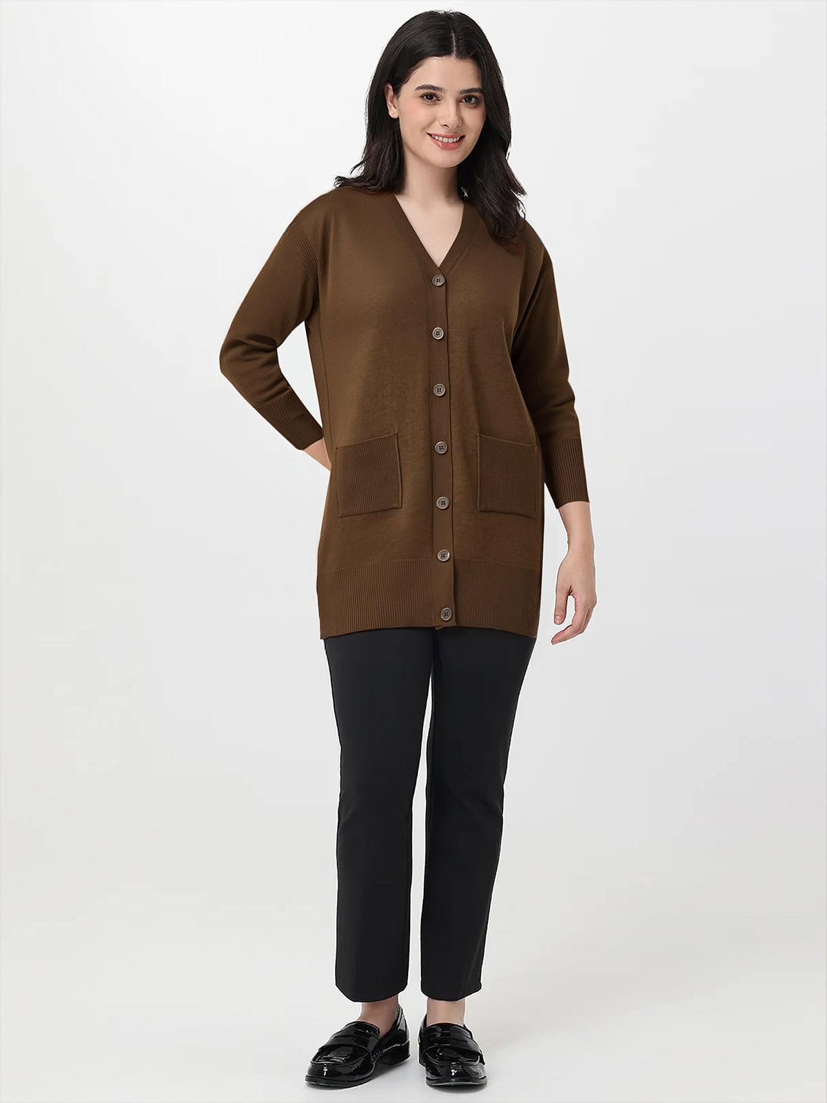 Woman wearing a brown cardigan over a black top and pants on a white background