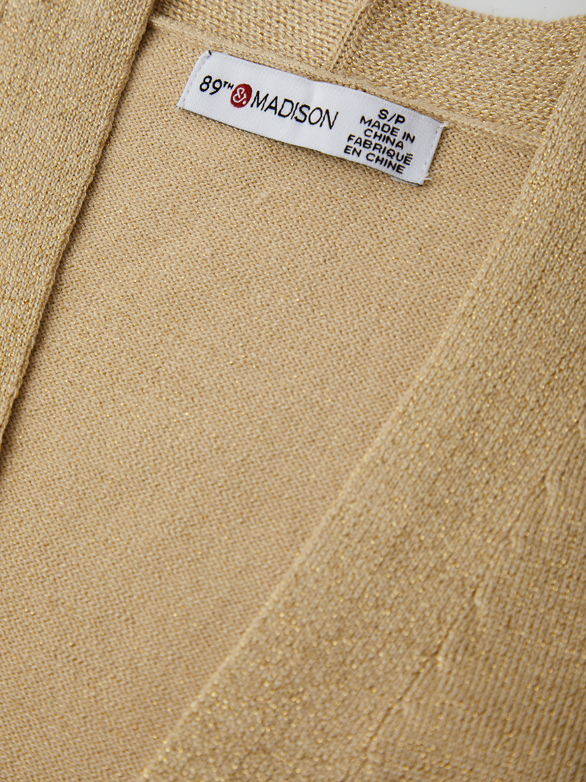 Close-up of a beige fabric with a label reading '89th & Madison' on a white background.