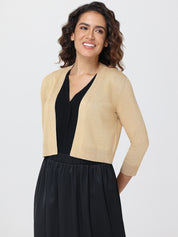 Woman wearing a beige cardigan over a black top and skirt on a white background