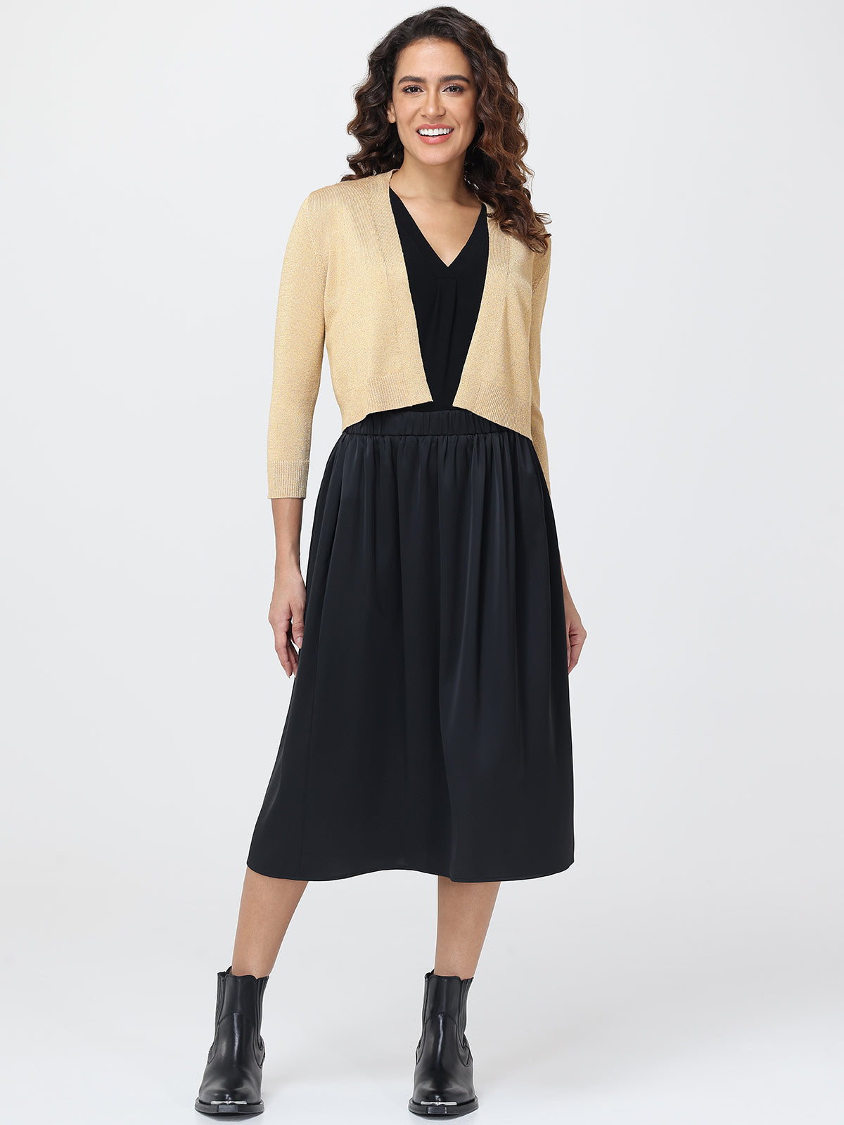 Woman wearing a black dress with a beige cardigan on a white background