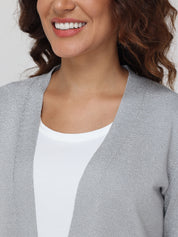 Woman wearing a gray cardigan over a white top against a light background
