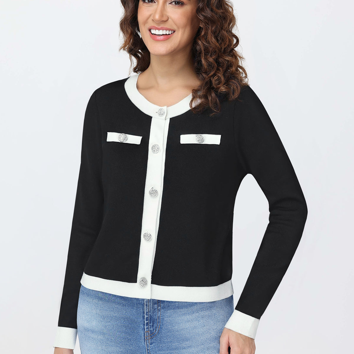Woman wearing a black and white cardigan with blue jeans on a white background