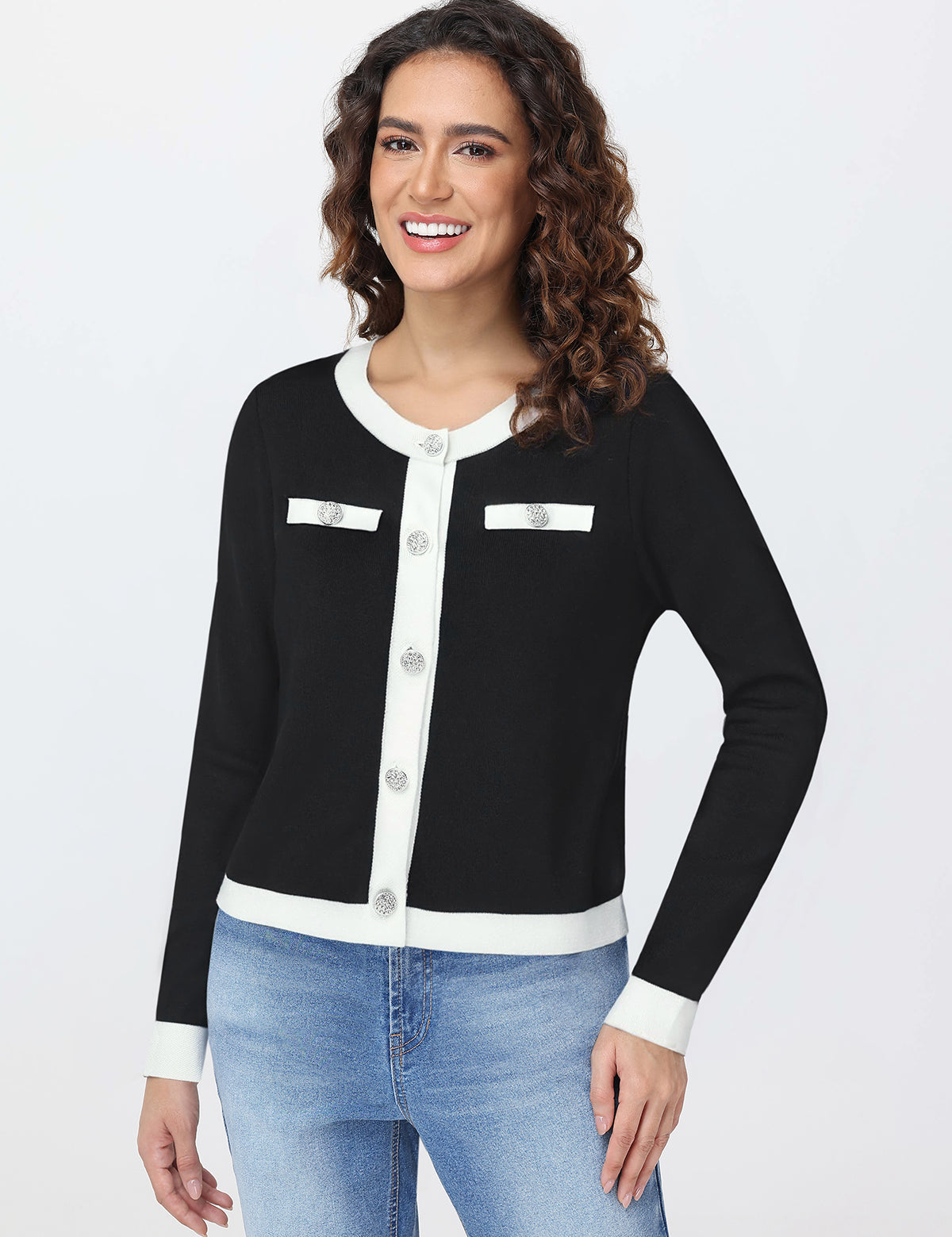 Woman wearing a black and white cardigan with blue jeans on a white background