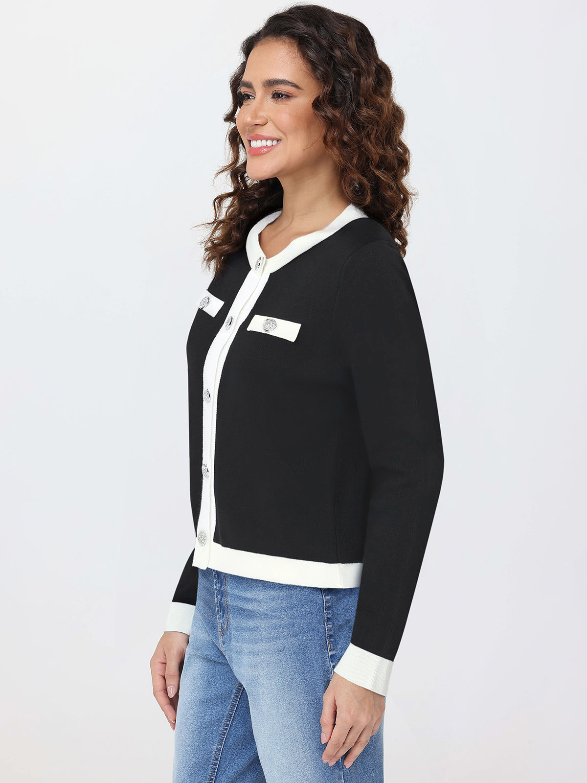 Woman wearing a black and white cardigan with blue jeans on a white background