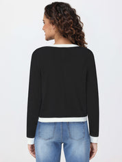 Woman wearing a black cardigan with white trim and blue jeans on a light gray background