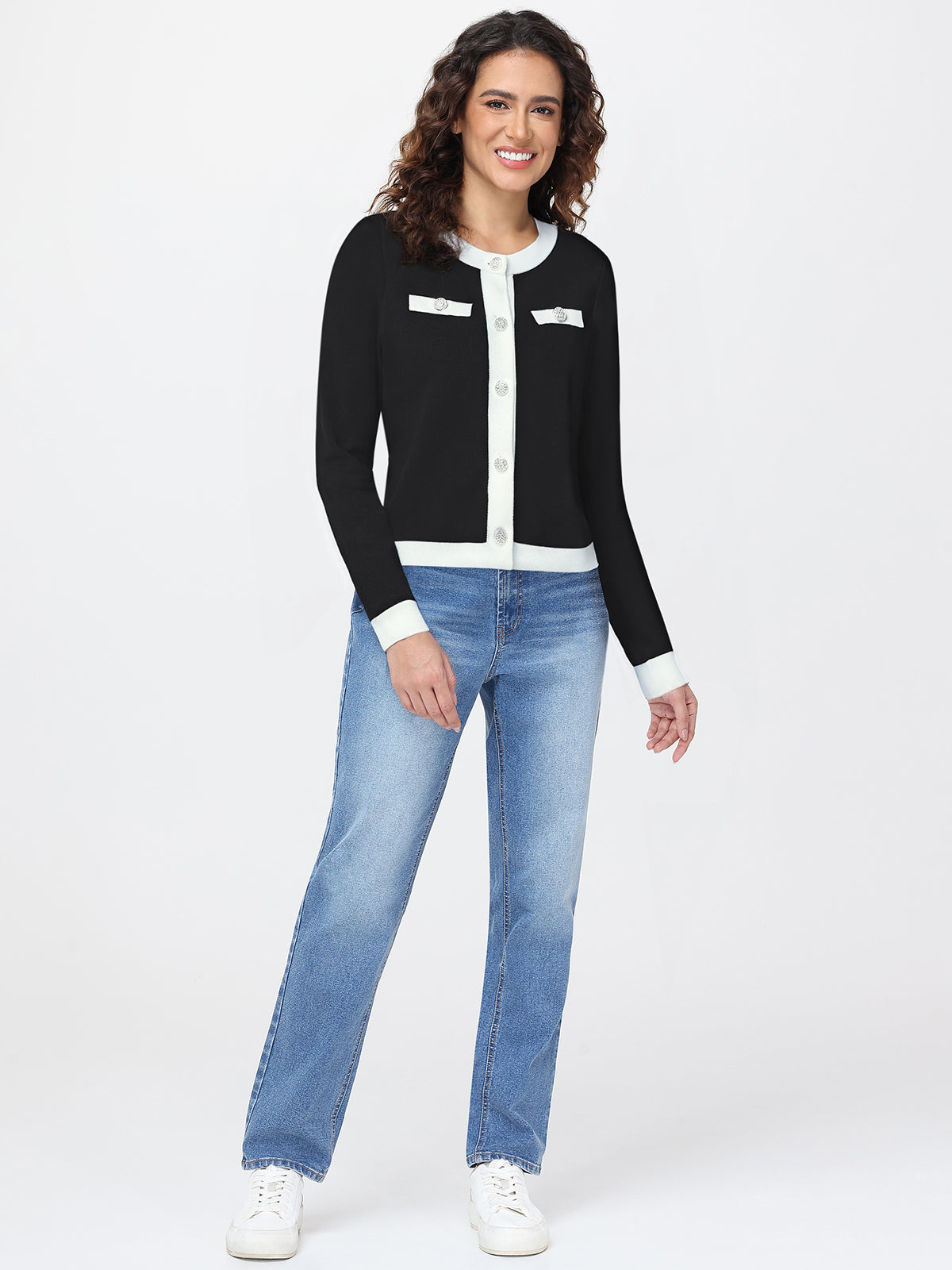 Woman wearing a black and white cardigan with blue jeans on a white background