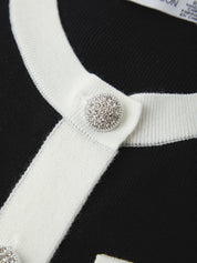 Close-up of a black and white striped garment with a decorative button.