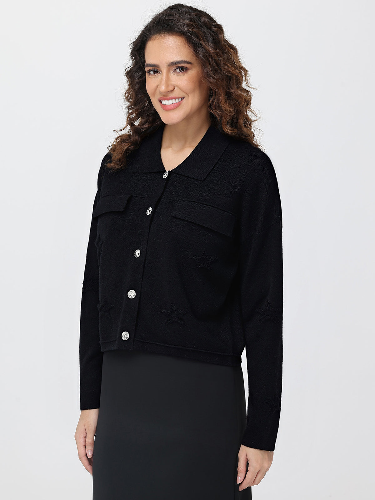 Woman wearing a black cardigan with silver buttons on a white background