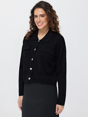 Woman wearing a black cardigan with silver buttons on a white background
