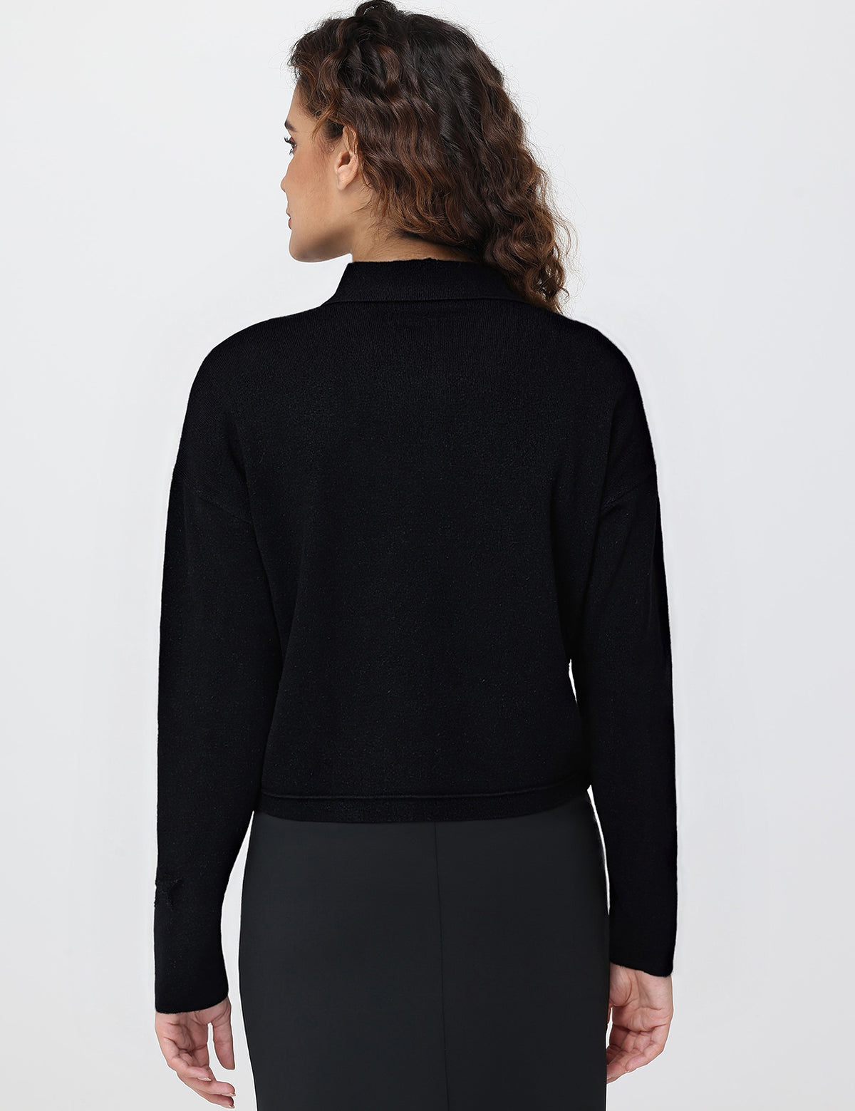 Person wearing a black long-sleeve cardigan against a white background