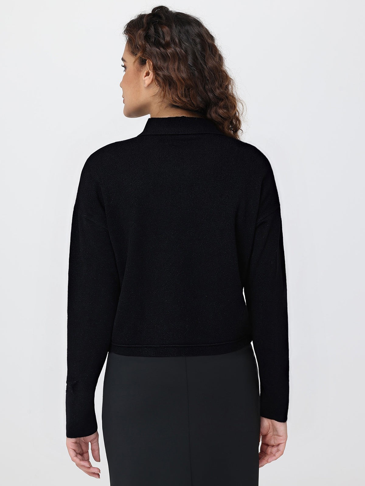 Person wearing a black long-sleeve cardigan against a white background