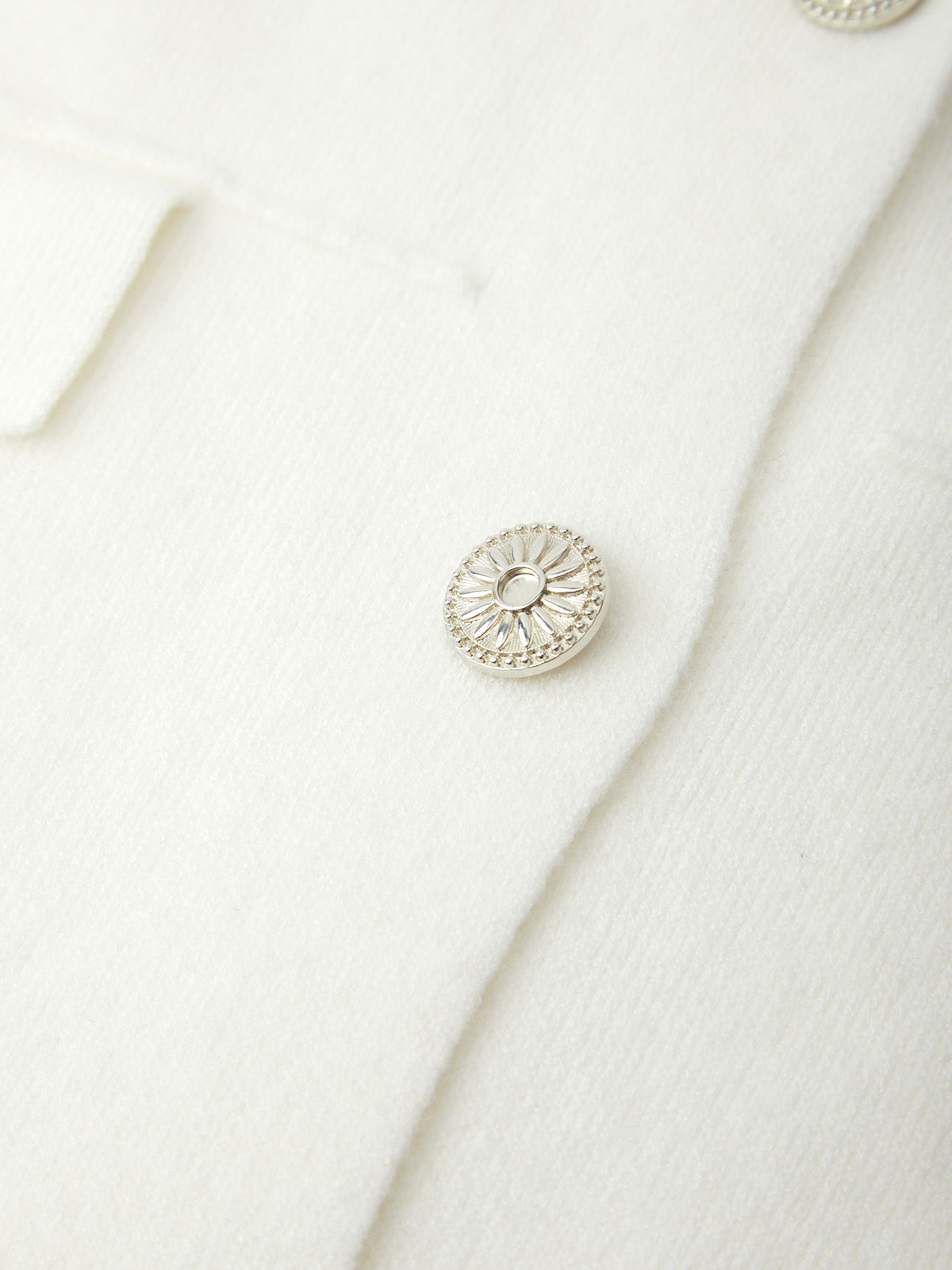 Close-up of a silver button on a white fabric background