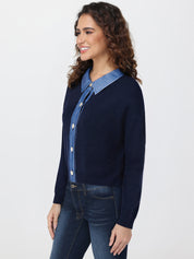 Woman wearing a navy cardigan over a denim shirt with jeans on a white background