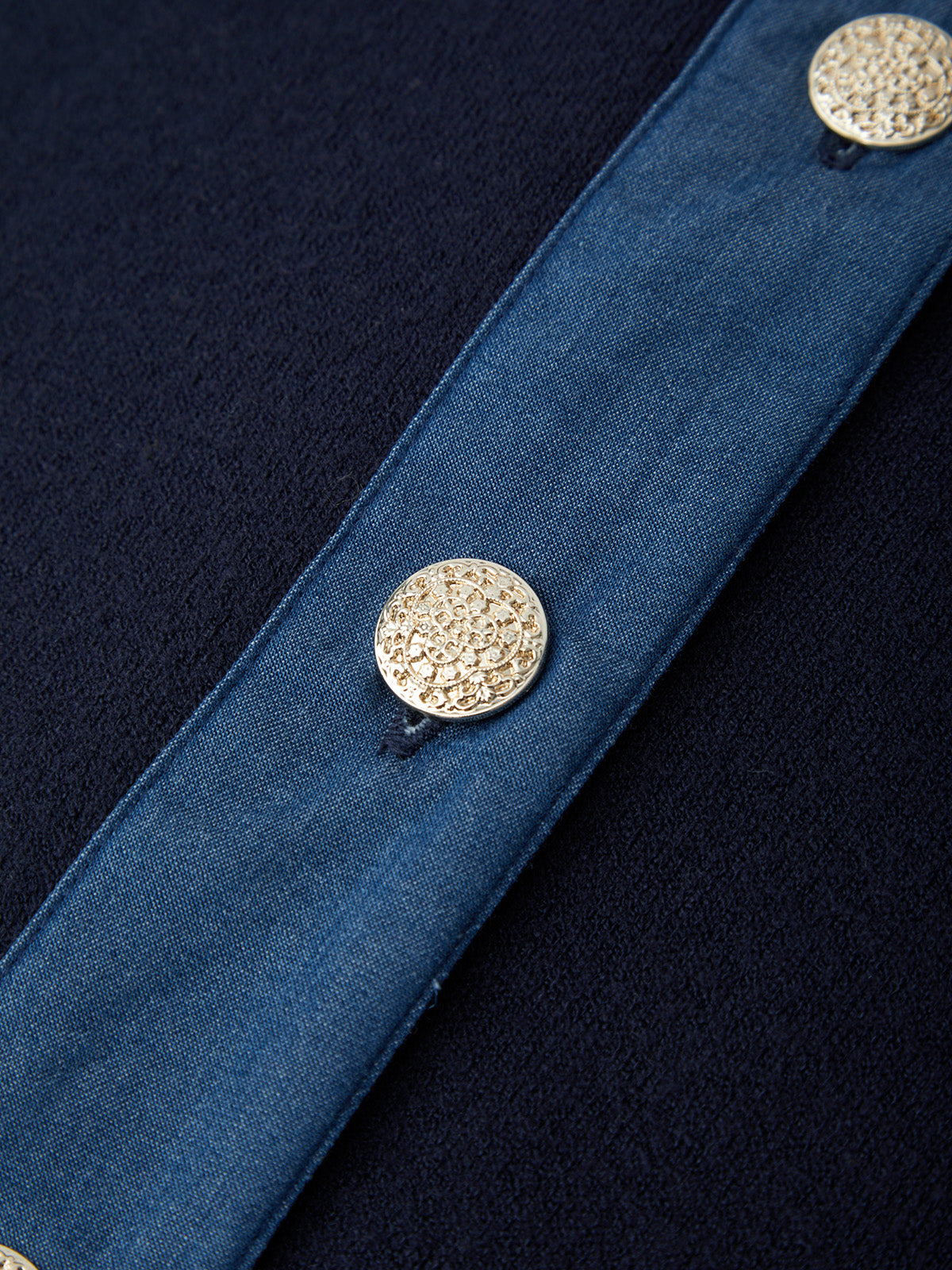 Close-up of a blue fabric with decorative buttons on a dark background
