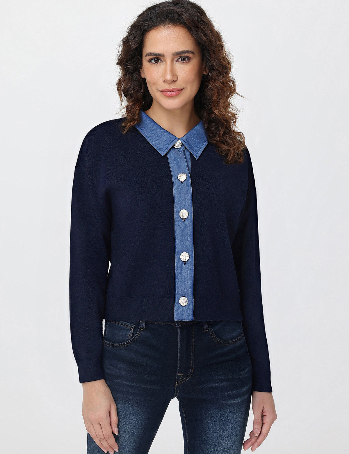 Woman wearing a navy cardigan over a blue denim shirt with a white background