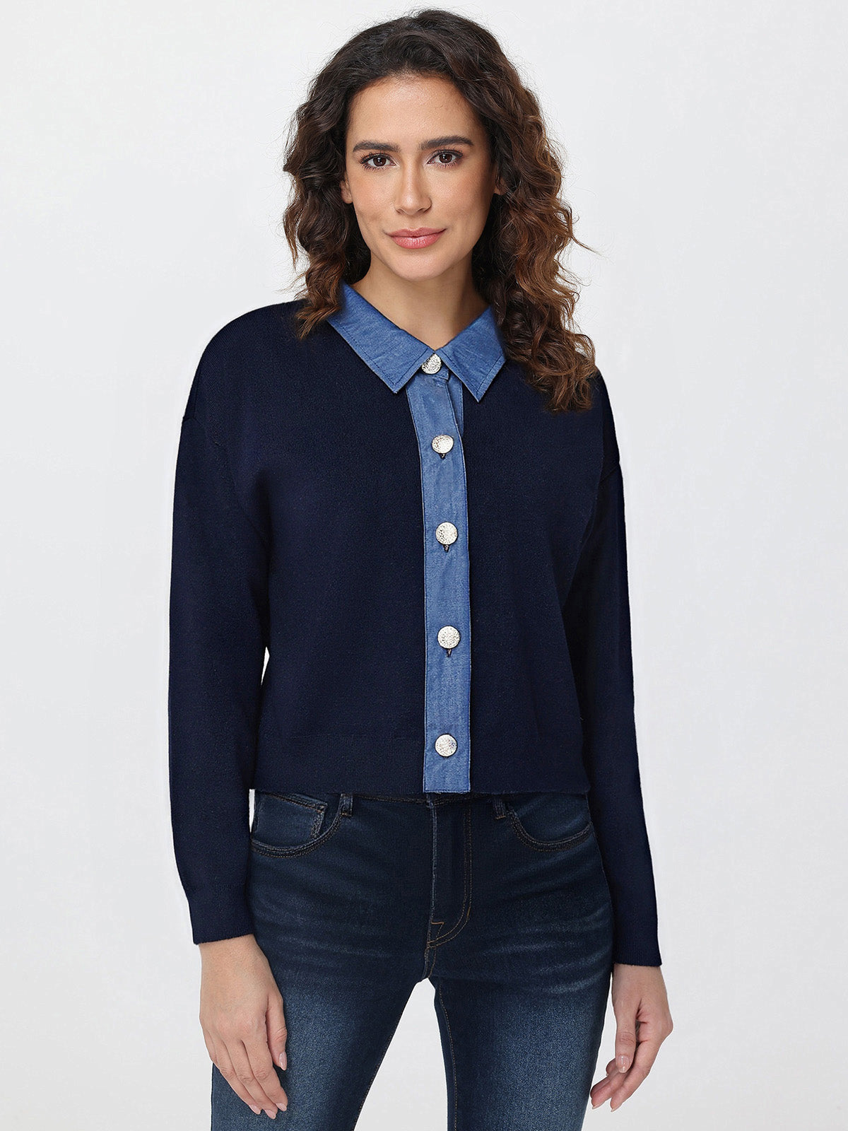 Woman wearing a navy cardigan over a blue denim shirt with a white background