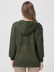 Person wearing a green hoodie with a textured pattern on a plain background