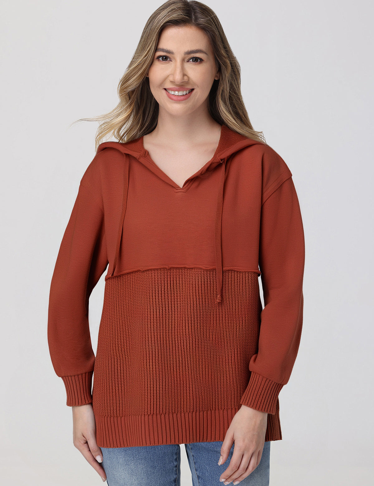 Woman wearing a rust-colored hoodie against a plain background