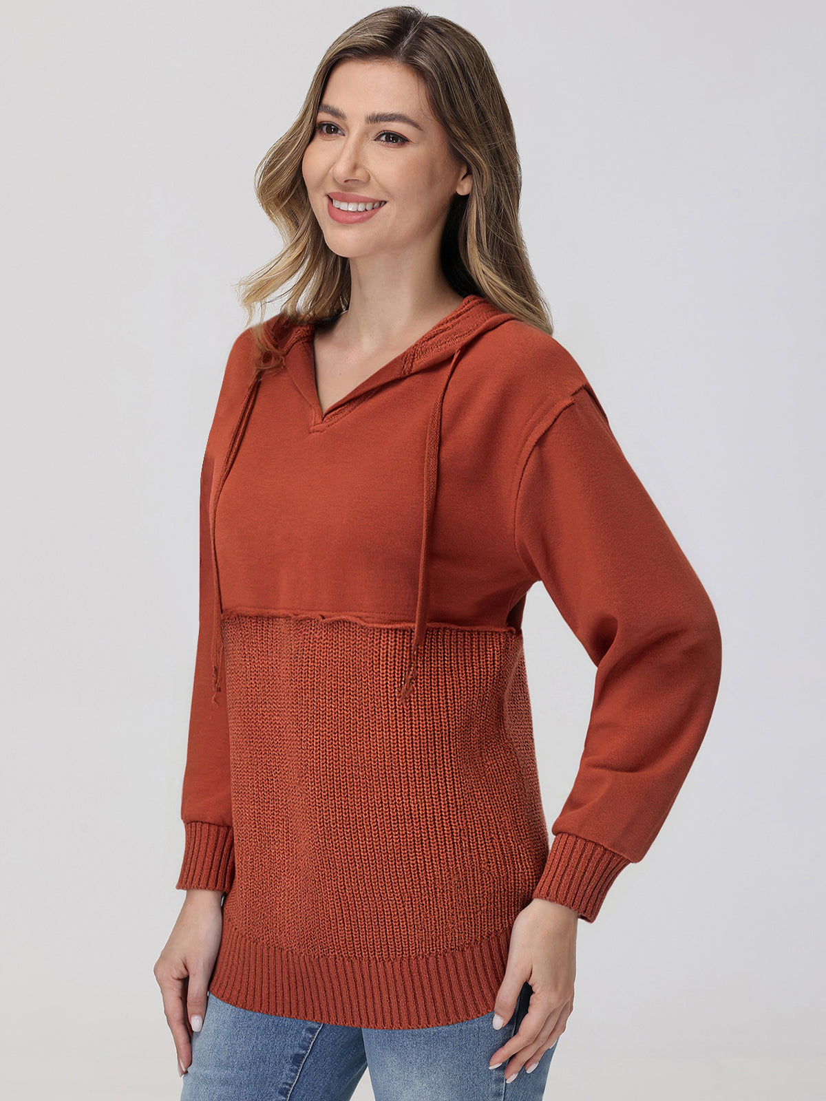 Woman wearing a rust-colored hoodie with a textured pattern on a plain background