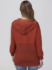 Person wearing a rust-colored hoodie on a plain background