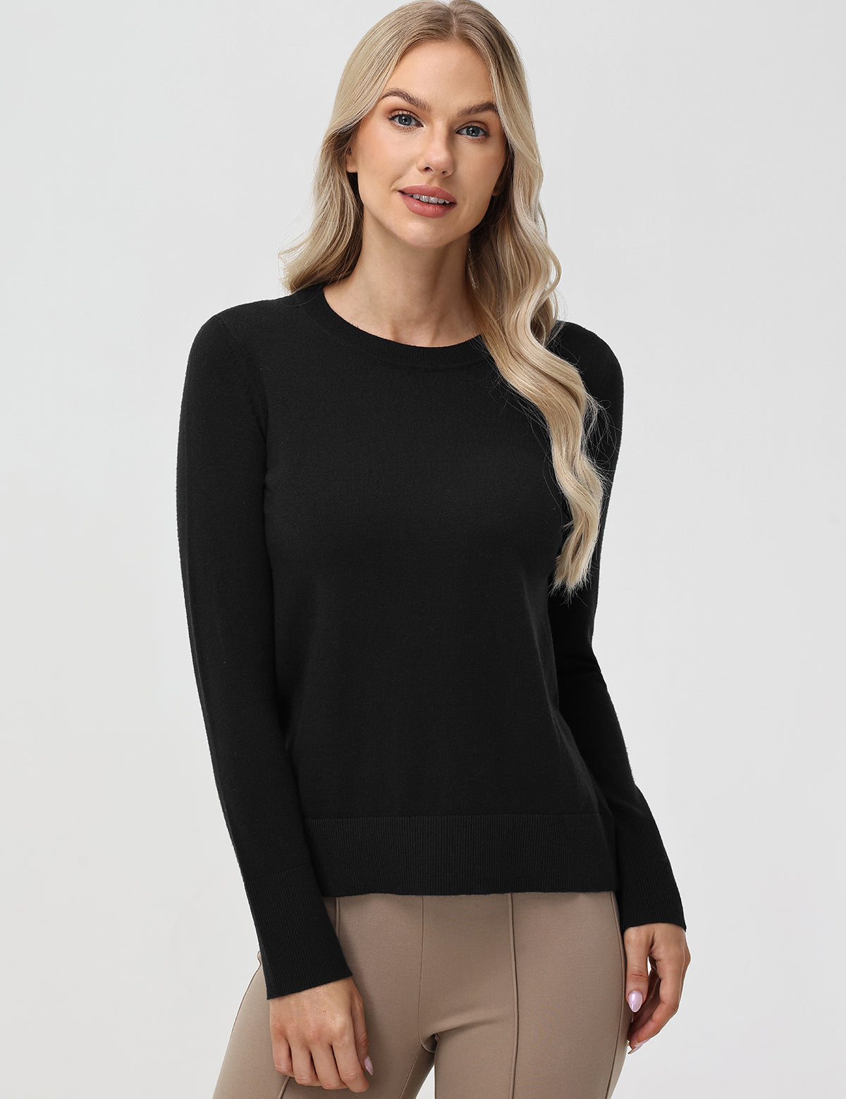 Woman wearing a black sweater and beige pants on a white background