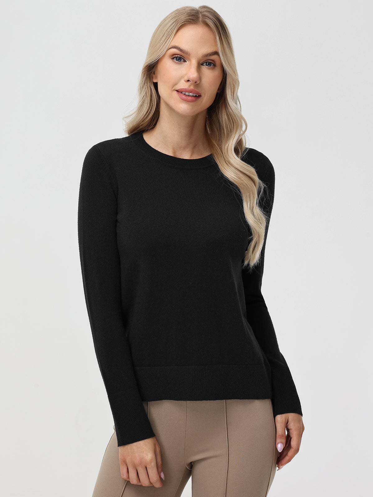 Woman wearing a black sweater and beige pants on a white background