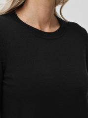 Close-up of a person wearing a black sweater with a neutral background