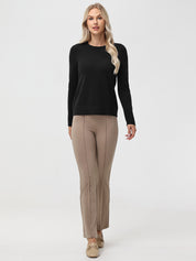 Woman wearing a black sweater and beige pants on a white background