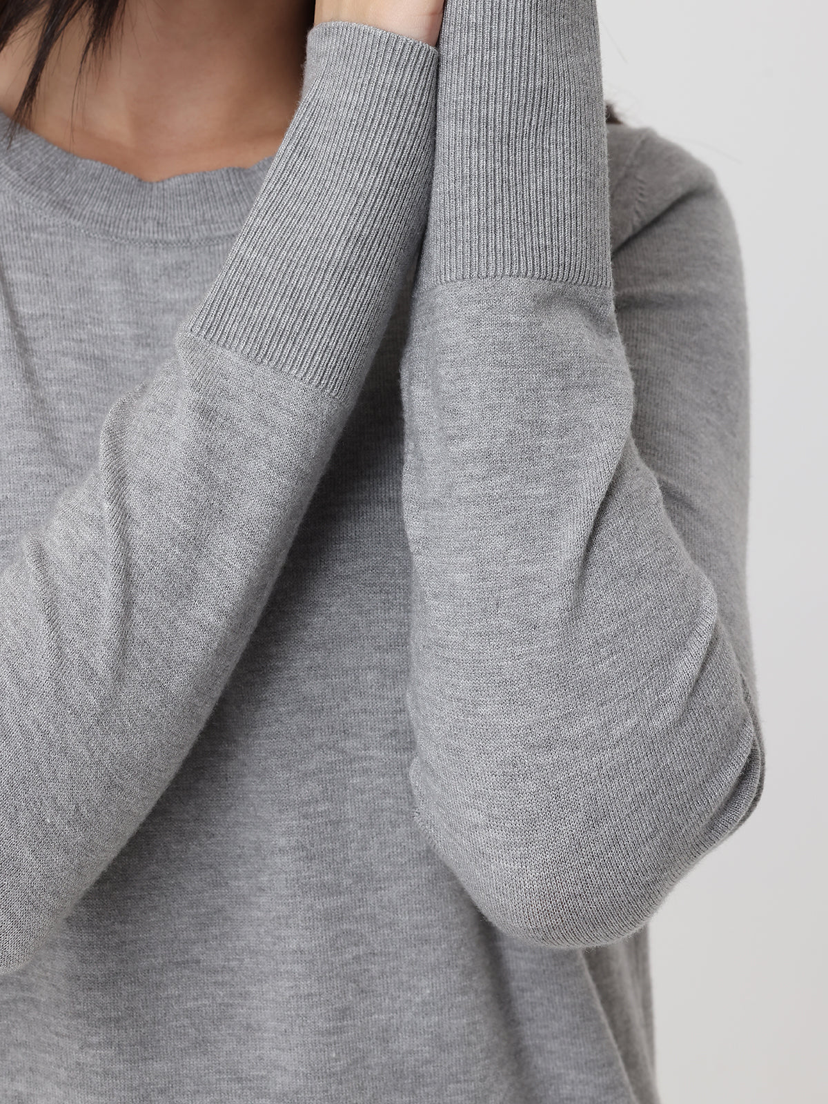Gray sweater with a focus on the sleeve and neckline against a neutral background
