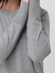 Gray sweater with a focus on the sleeve and neckline against a neutral background