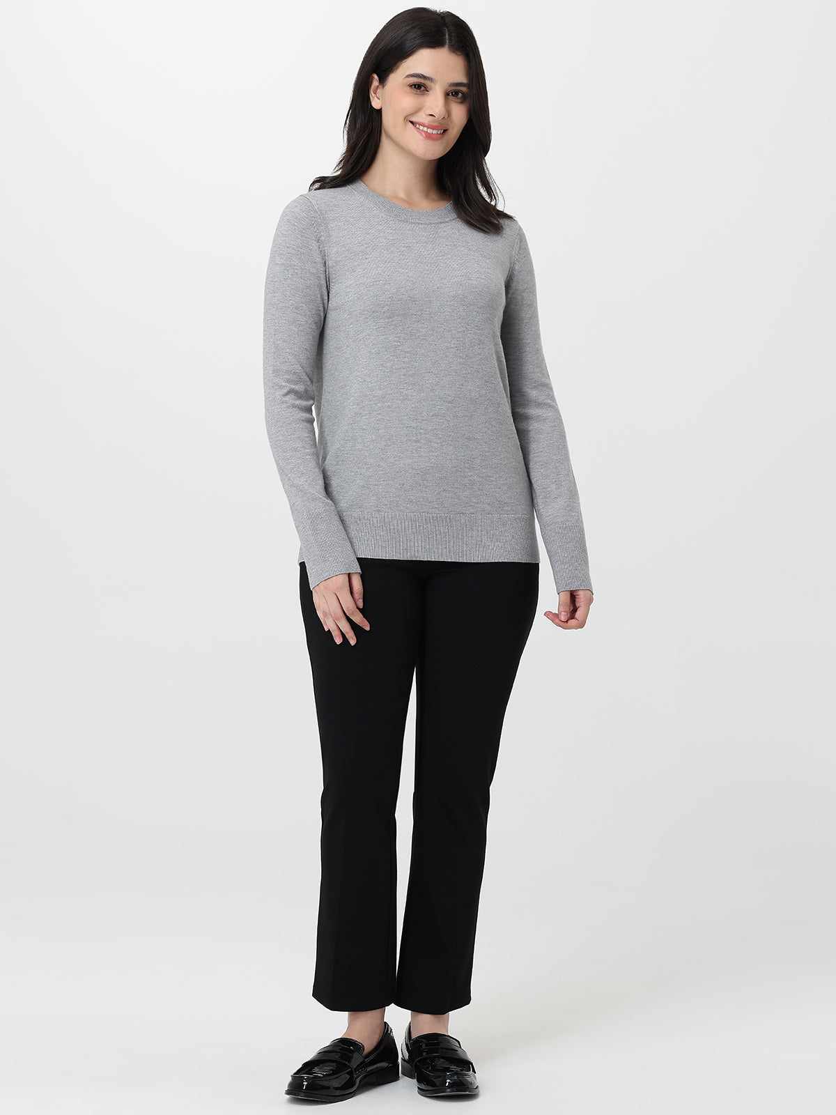 Woman wearing a gray sweater and black pants on a white background