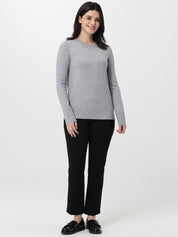 Woman wearing a gray sweater and black pants on a white background