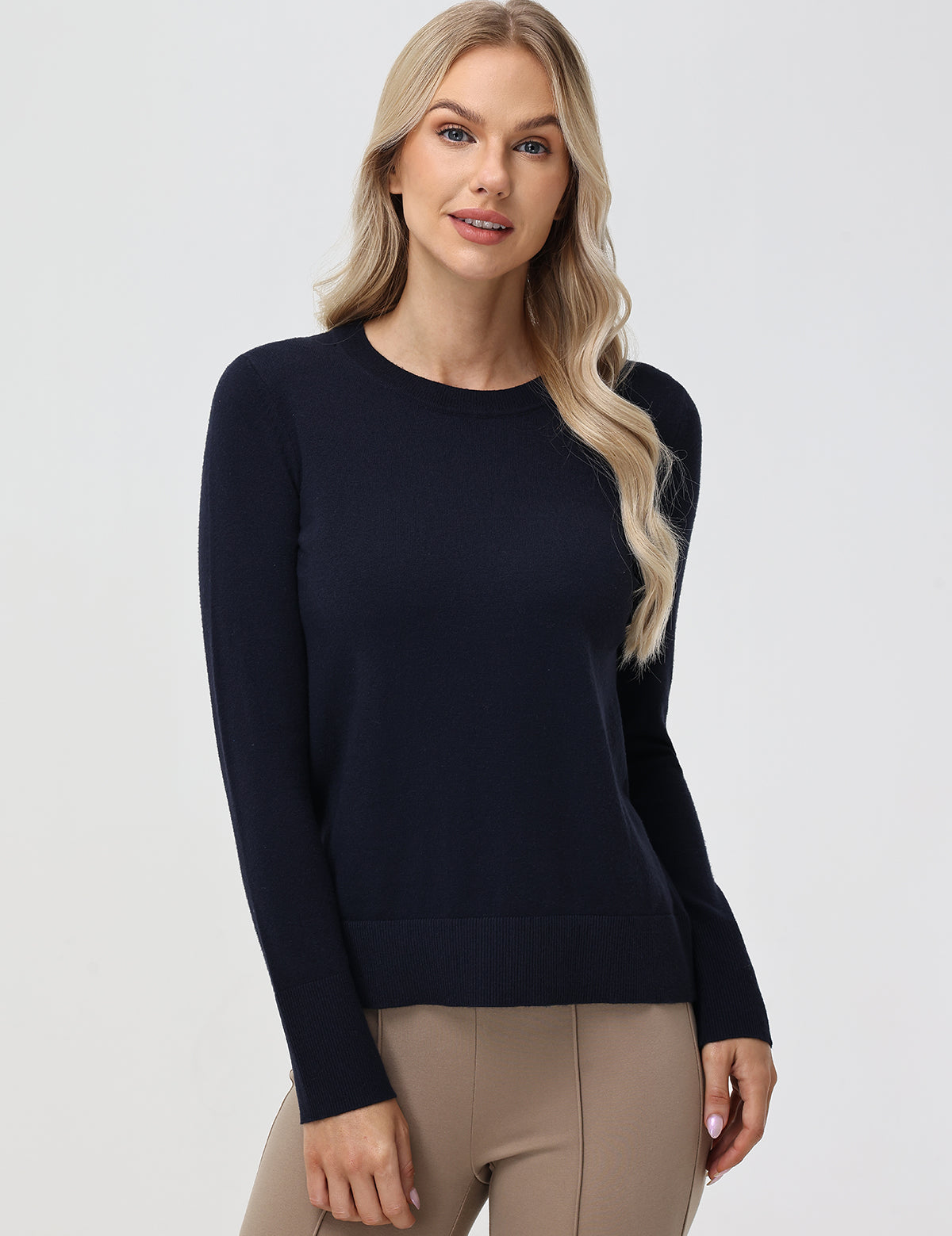 Woman wearing a navy sweater and beige pants on a white background