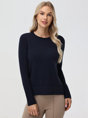 Woman wearing a navy sweater and beige pants on a white background
