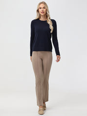 Woman wearing a navy sweater and beige pants on a white background