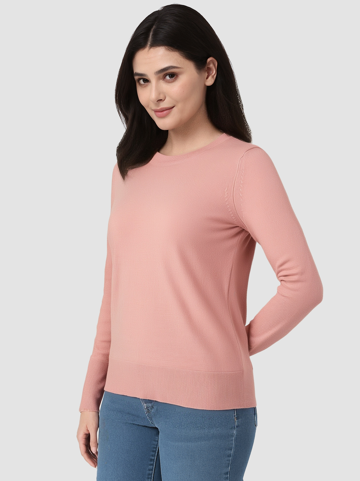 Woman wearing a pink long-sleeve top and blue jeans on a white background