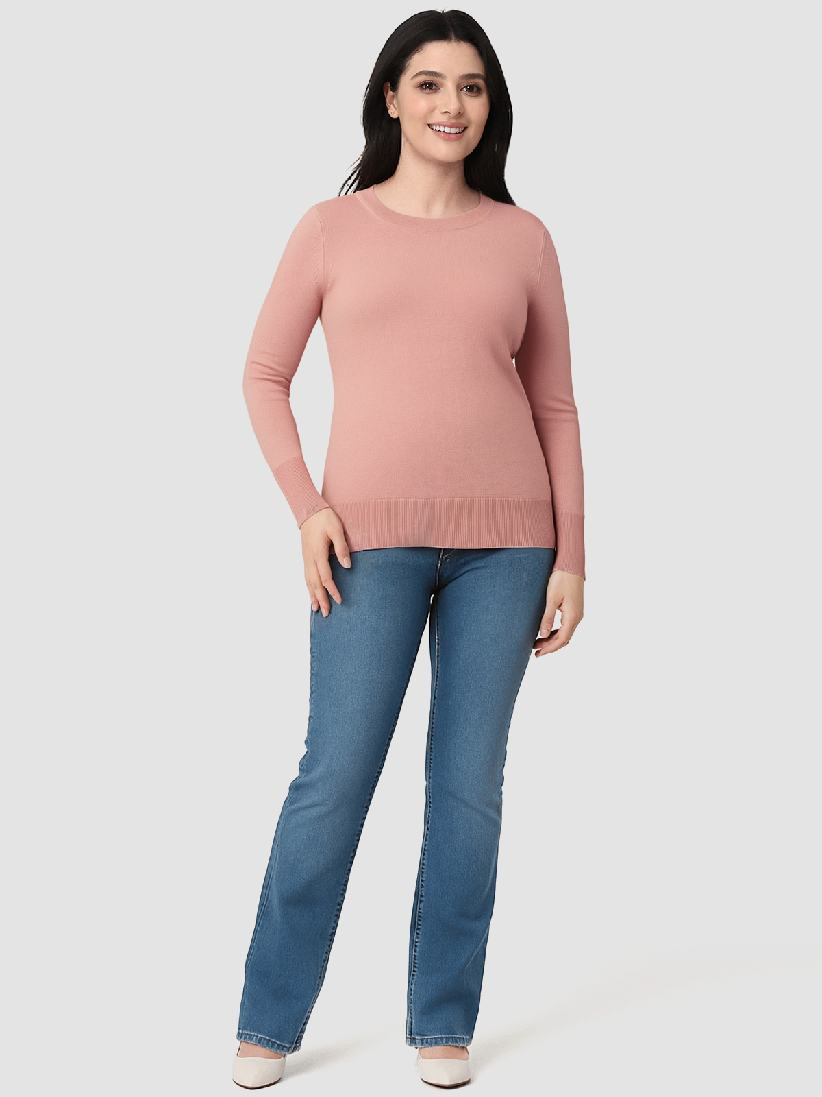 Woman wearing a pink sweater and blue jeans on a white background