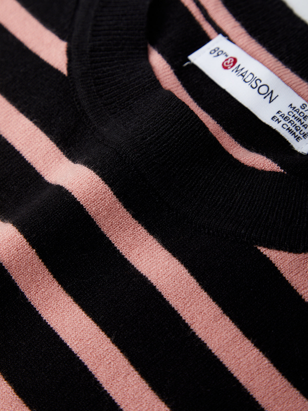 Close-up of a striped garment with a label on a black and pink background