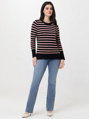 Woman wearing a black and pink striped sweater with blue jeans on a white background