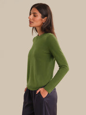 Woman wearing a green sweater against a beige background